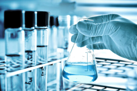 45720416 - flask in scientist hand and laboratory glassware background