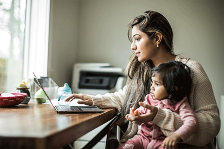 Woman on laptop holding child