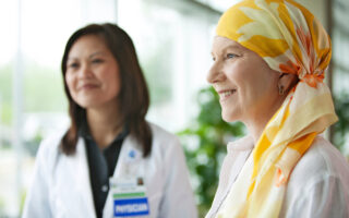 Mature woman with cancer standing with doctor at hospital